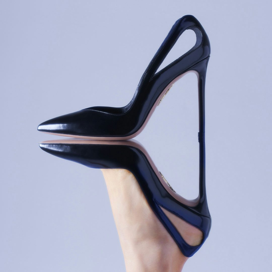 Emphasizing the sleek lines and playful shapes of our Sheeva Pumps, the picture illustrates the black leather version standing upon an upside-down foot that wears what would otherwise be its mirror image.